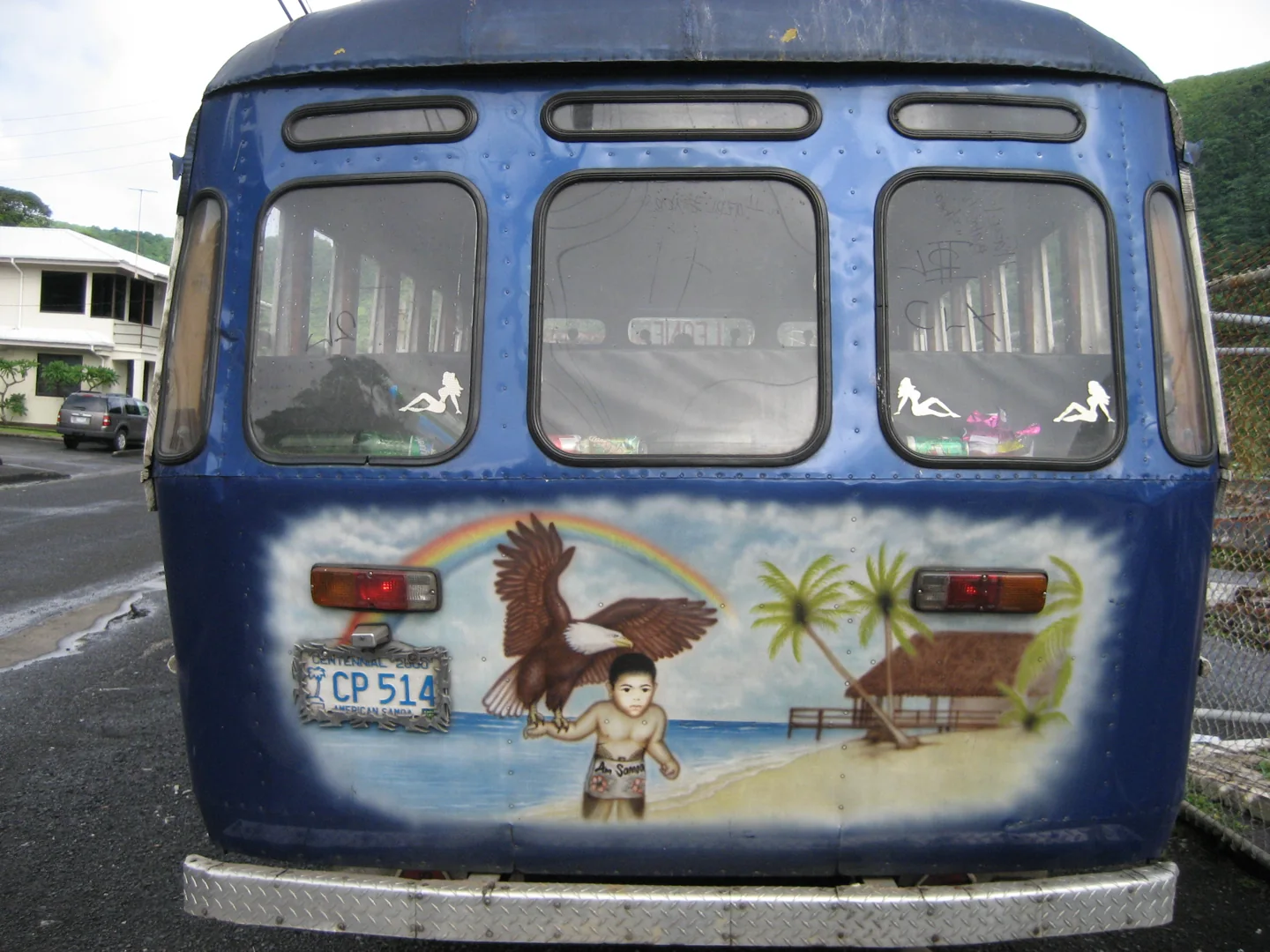 Rear of a blue Tutuila bus decorated with an eagle, palm tree and Samoan scene