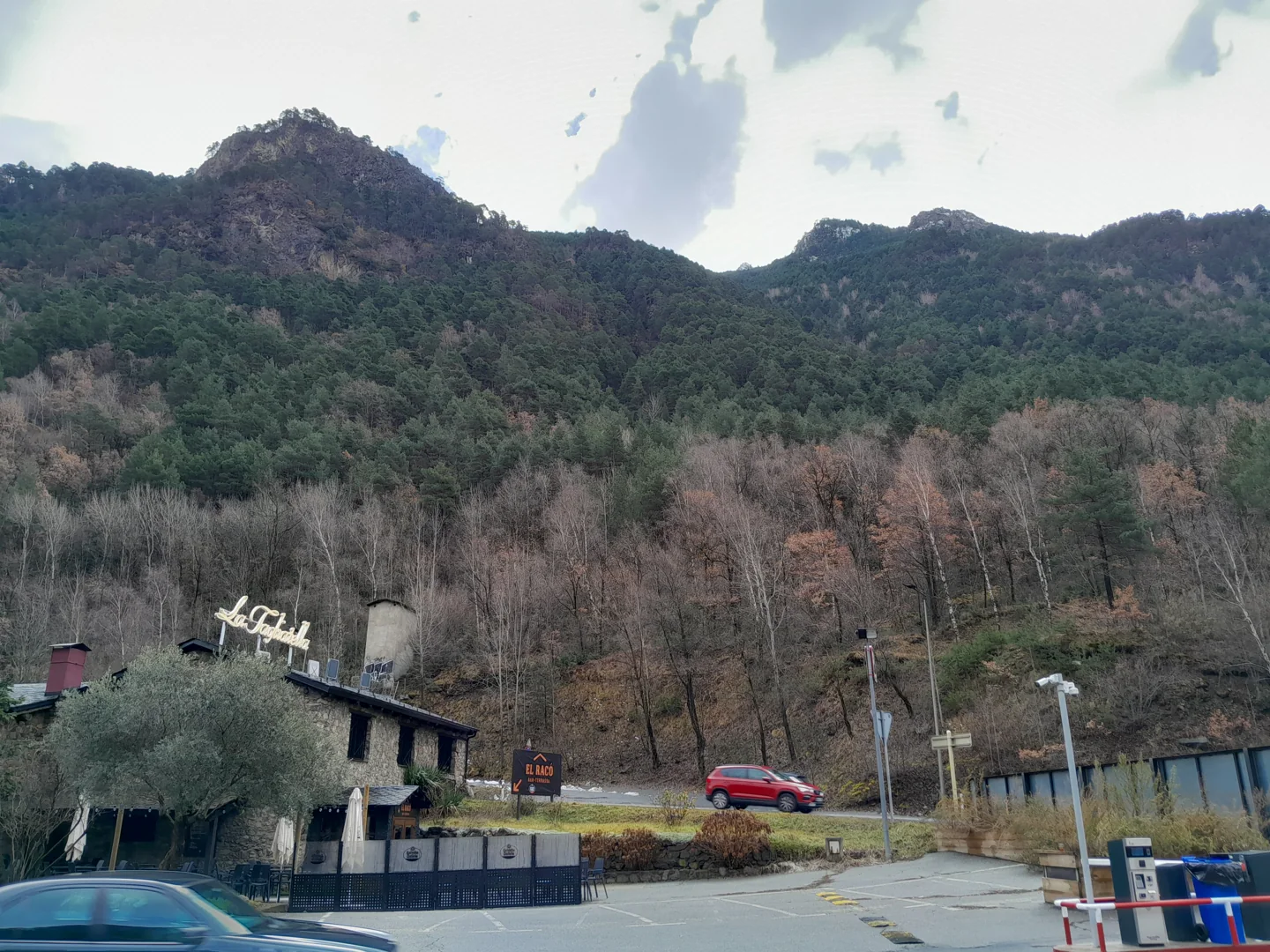 Wooded mountain slope, bare trees and roadside buildings in Andorra la Vella in December