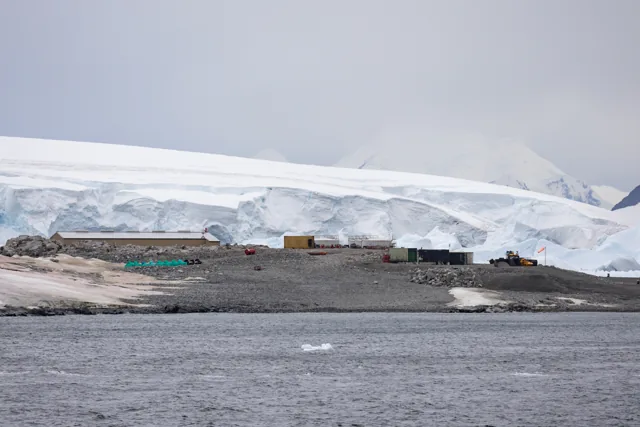 Rothera research station buildings beside snow-covered mountains and coastal water