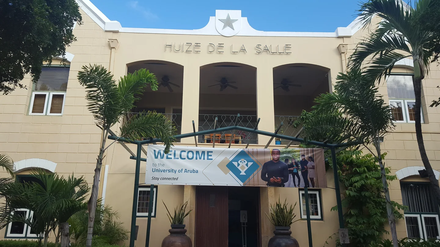 Palm trees and entrance facade marked Huize de la Salle at the University of Aruba