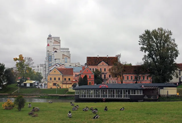 Historic buildings in Minsk’s Trinity Suburb beyond a grassy public space in rainy weather