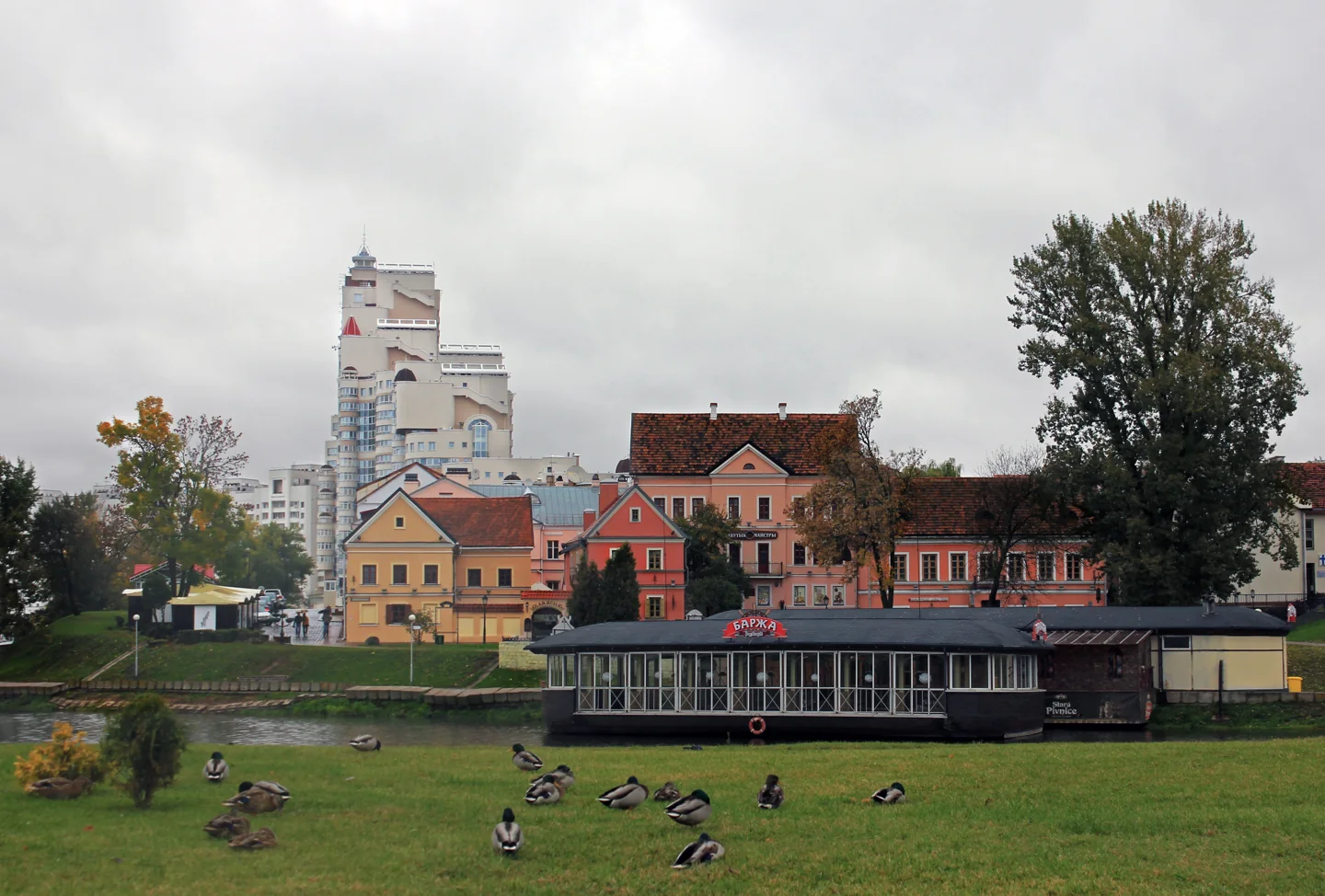 Historic buildings in Minsk’s Trinity Suburb beyond a grassy public space in rainy weather