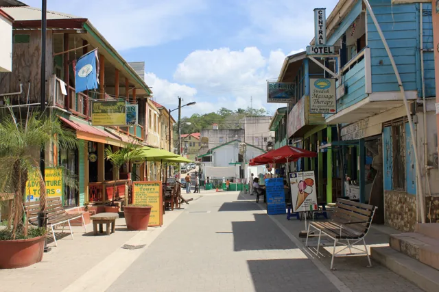 A paved pedestrian streetscape on Burns Avenue lined with colourful buildings, benches and awnings.