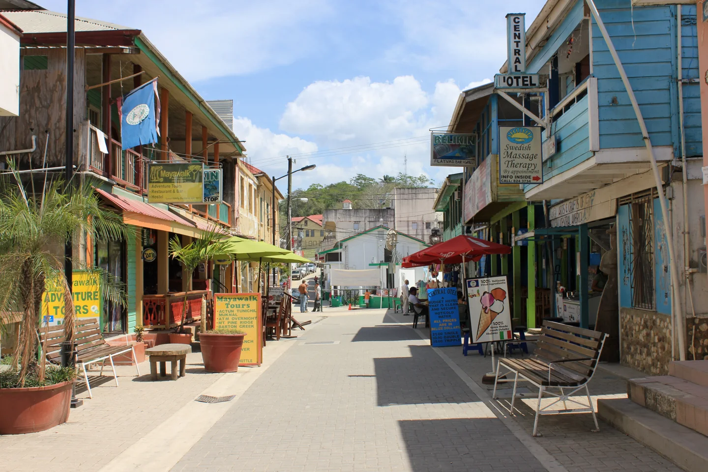 A paved pedestrian streetscape on Burns Avenue lined with colourful buildings, benches and awnings.