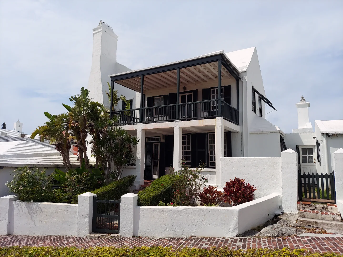 White Bridge House with dark shutters, a covered balcony and garden in St. George's