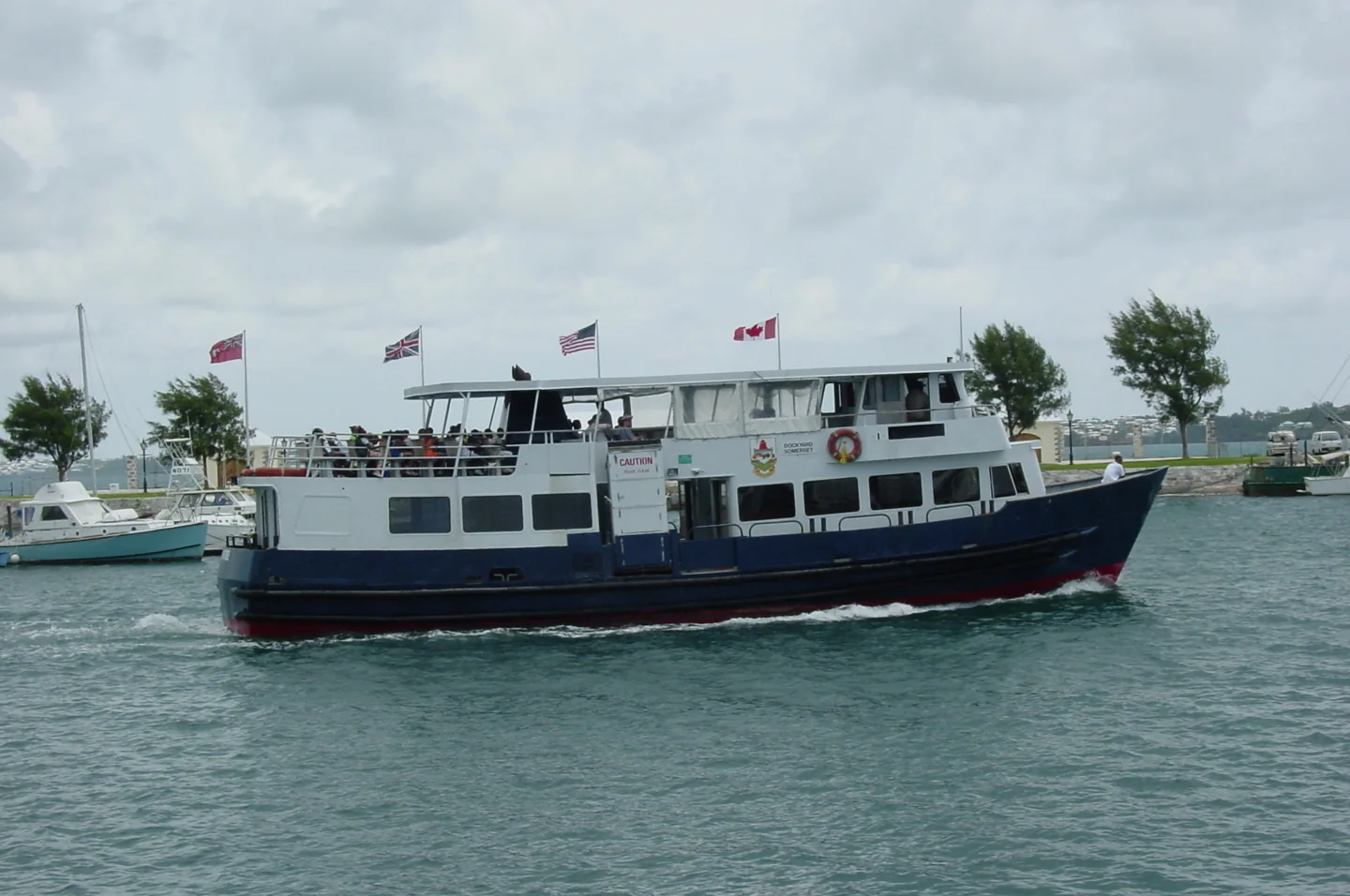 Blue and white passenger ferry moving away from Dockyard