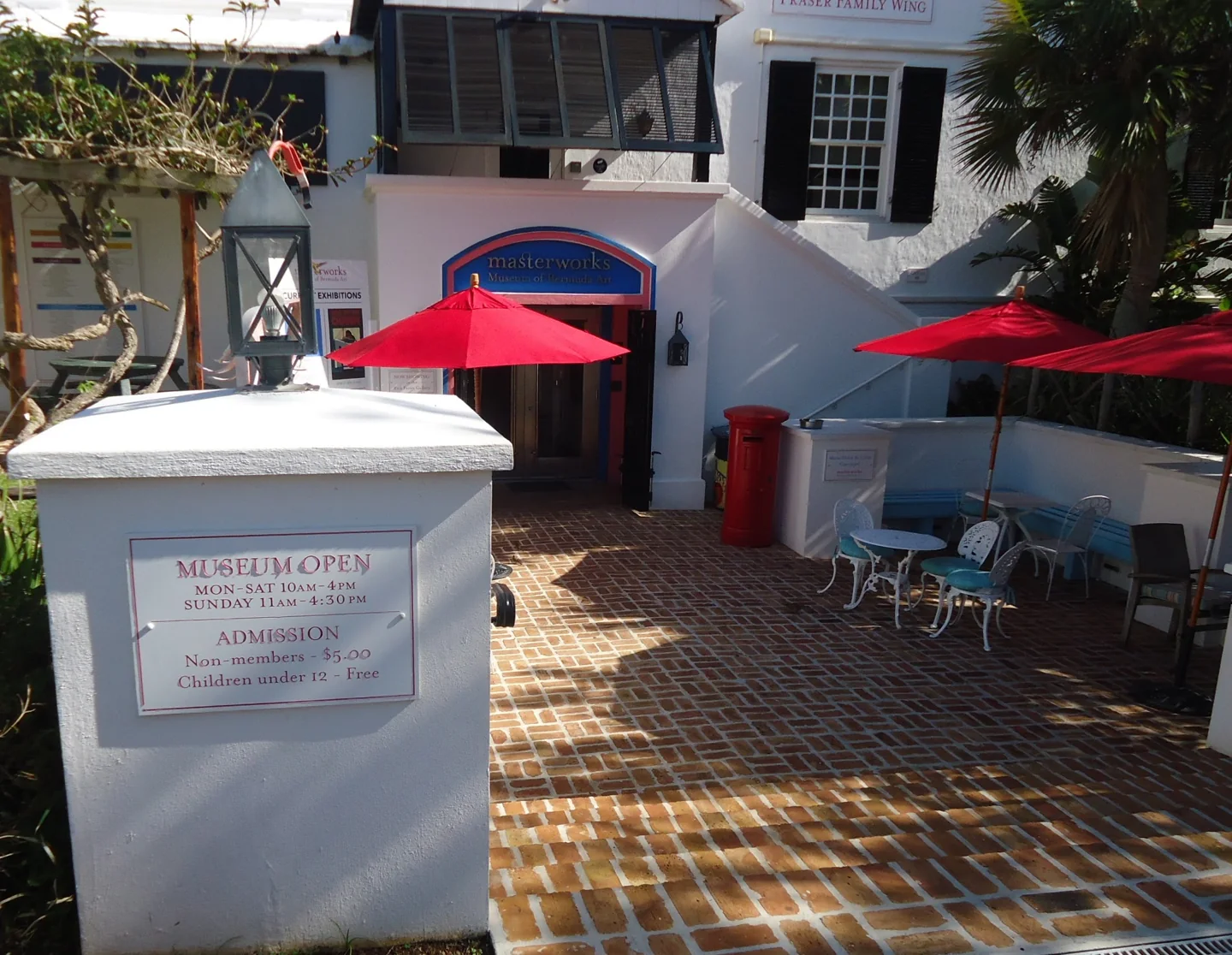 Brick museum courtyard with red umbrellas, white walls and outdoor seating at the Botanical Gardens