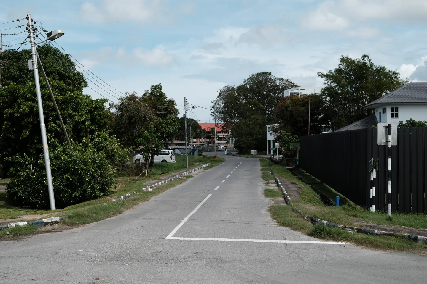 Jalan Sultan street in Kuala Belait lined with buildings, cars and roadside trees
