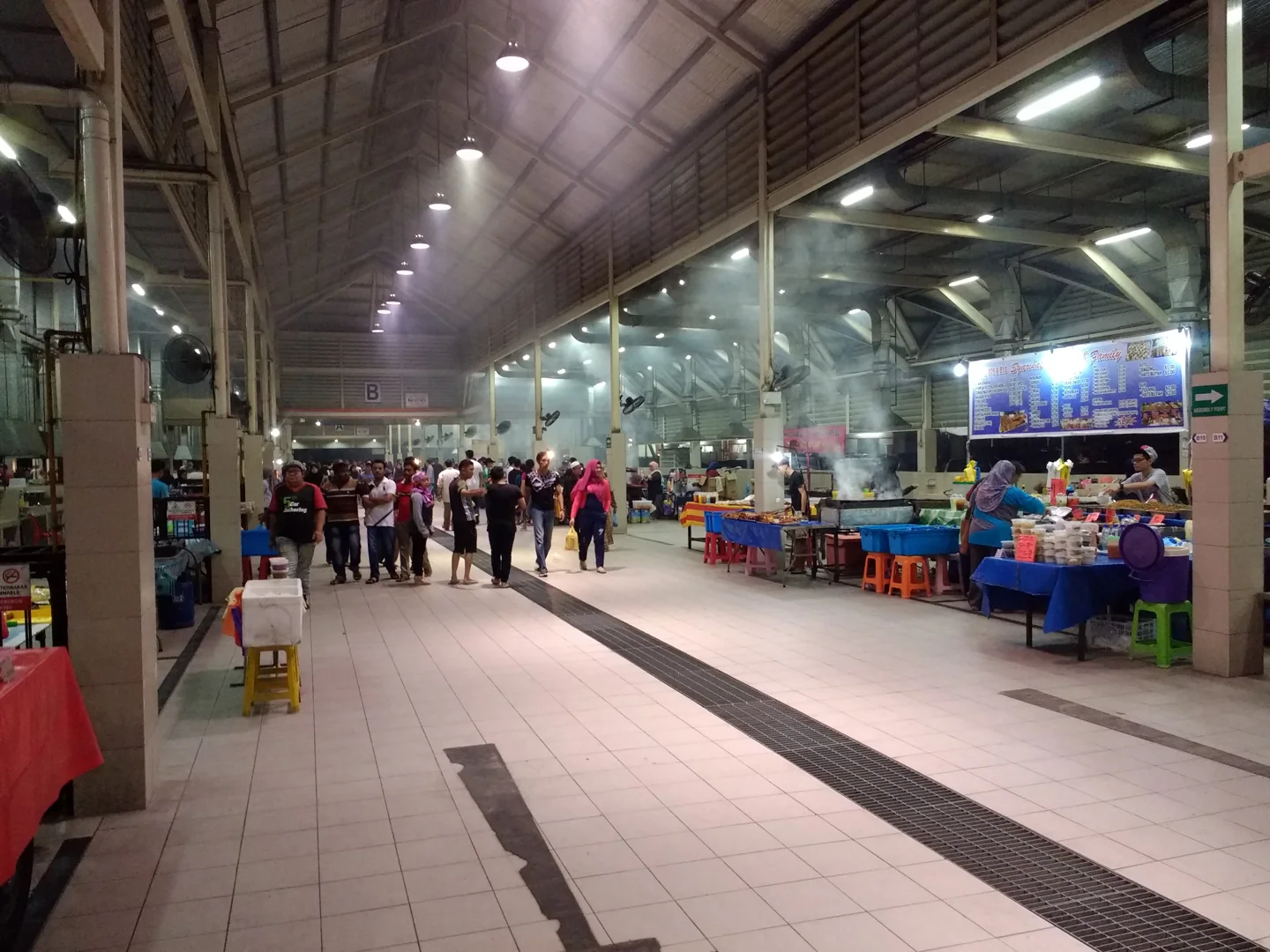 People buying prepared food at illuminated stalls in Gadong Night Market