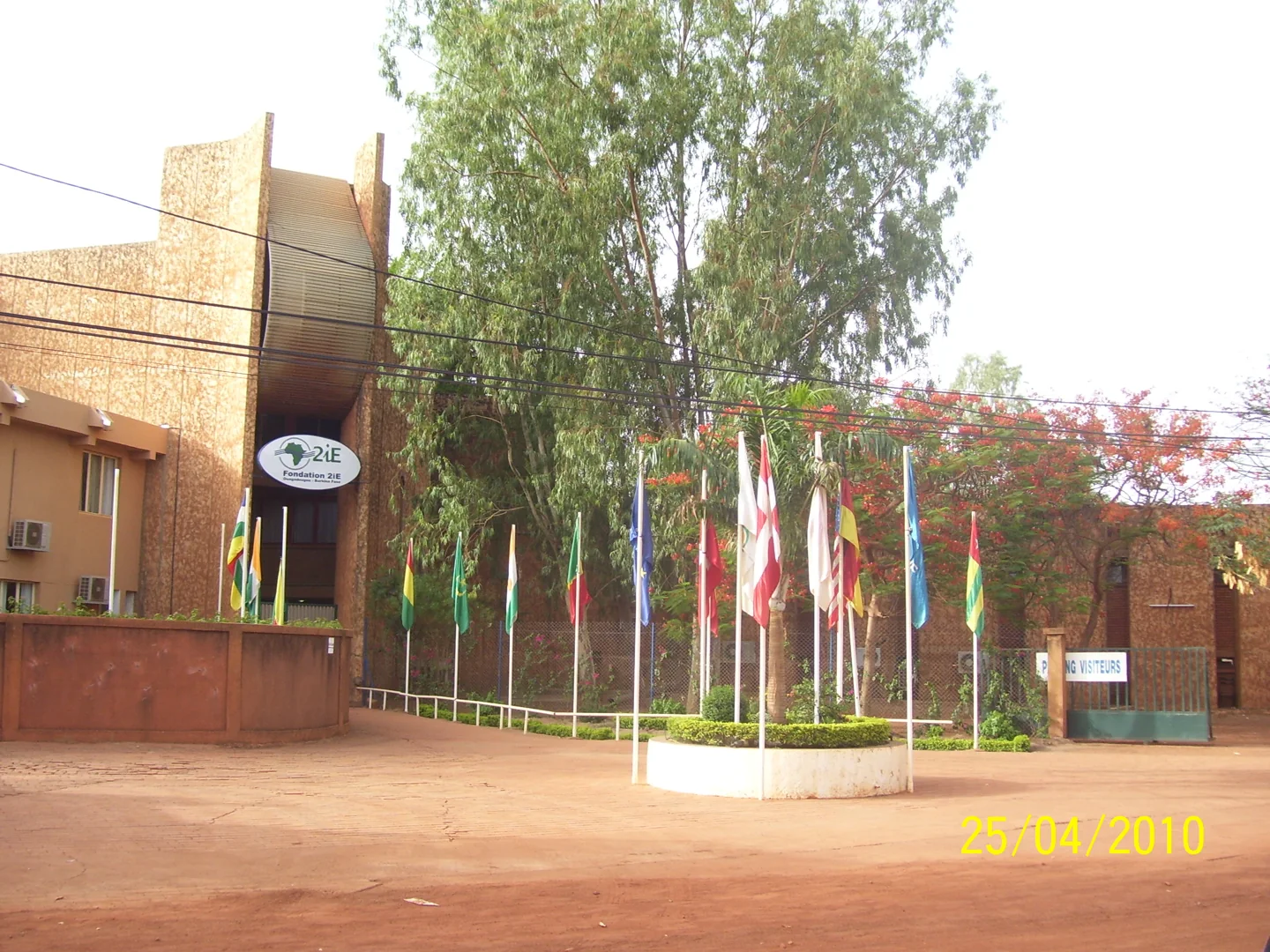 The entrance and buildings of 2iE in Ouagadougou with trees and national flags
