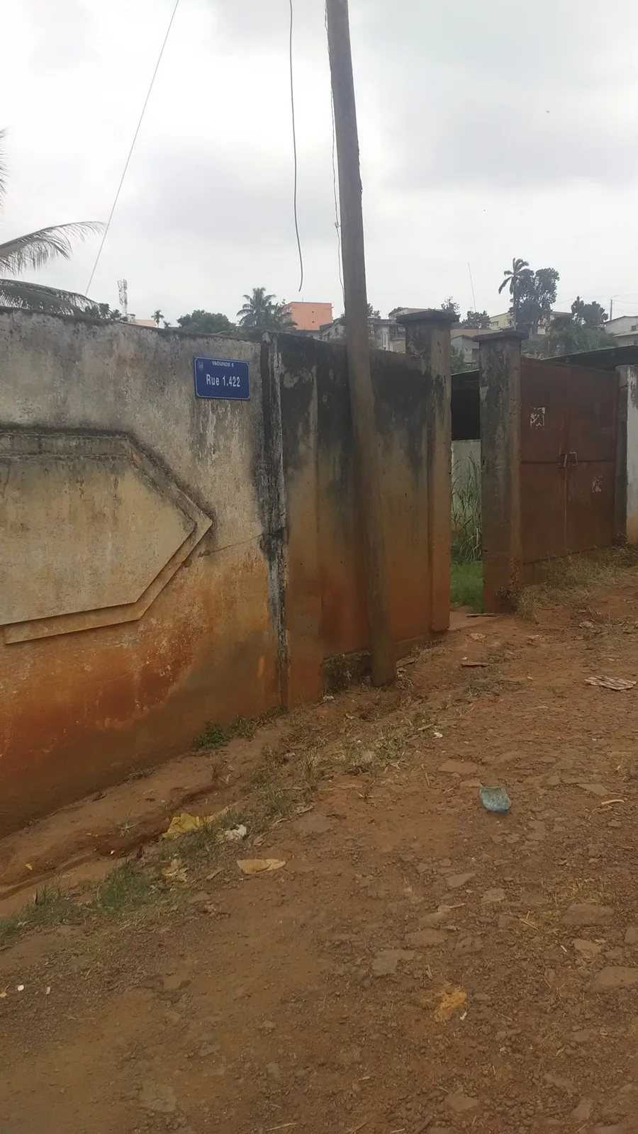 Rue 1.422 address sign beside a wall and gate in Yaoundé