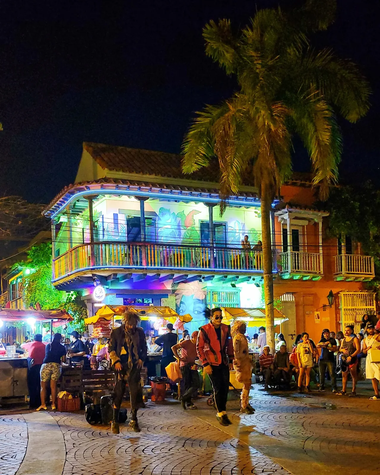 People, vendors and an illuminated building in Getsemani at night