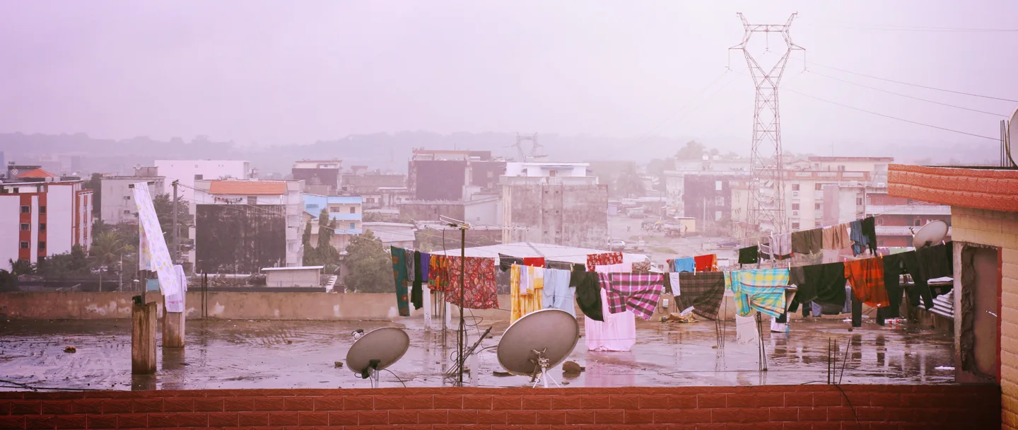 Laundry, satellite dishes and residential rooftops in the rain in Cocody, Abidjan