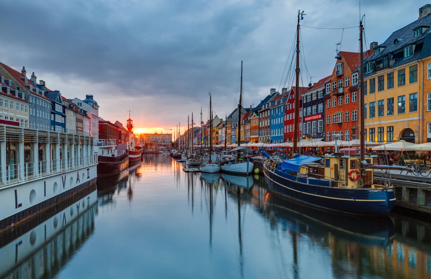 Colourful buildings and moored boats reflected in Copenhagen’s Nyhavn canal at sunset