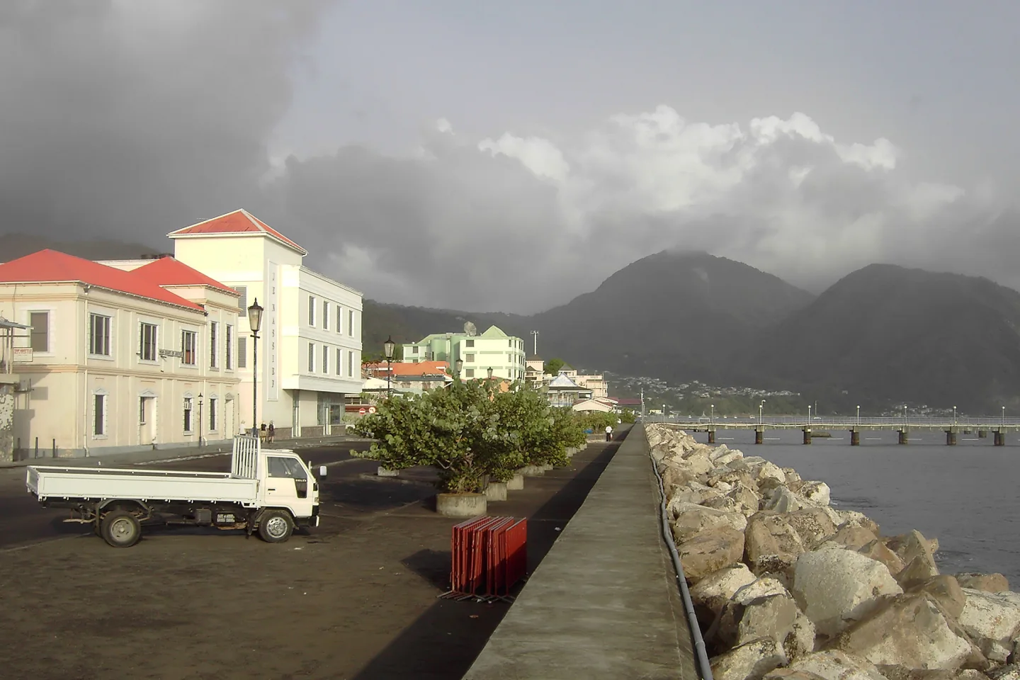 Roseau waterfront buildings and a sea wall with green hills behind